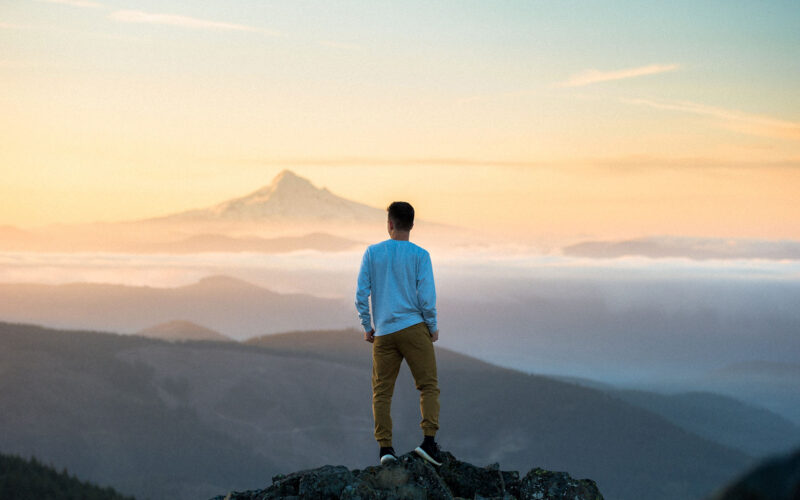man asking himself self improvement questions on top of mountain
